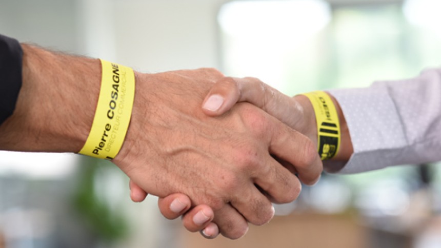 due persone che indossano dei braccialetti identificativi stampati che si danno la mano
