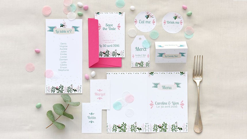 Scrivania con fogli di carta, penne, una pianta e un quaderno rosa con etichette adesive stampate