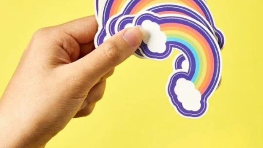 Mano che tiene adesivi stampati a forma di arcobaleno