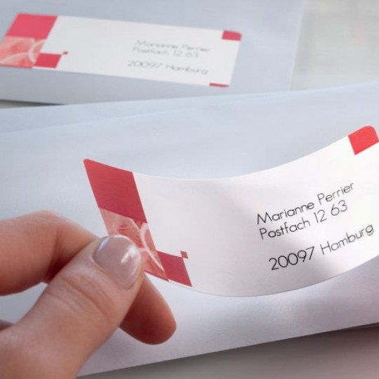 mani che applicano una etichetta stampata su una busta da lettere