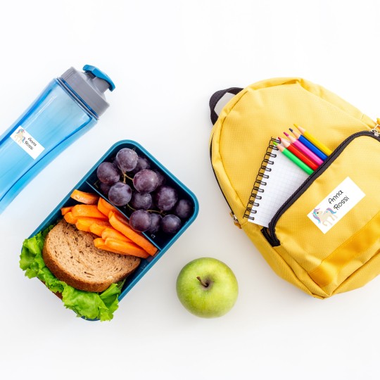 materiale scolastico disposto su un tavolo con applicate delle etichette stampate