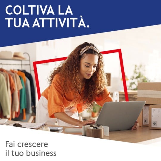 ragazza che lavora al computer all'interno di un negozio accanto a dei pacchi con le etichette applicate