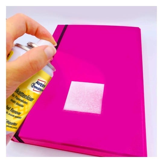 mano che mostra come rimuovere una etichetta da una cartellina con lo spray rimuovi etichette