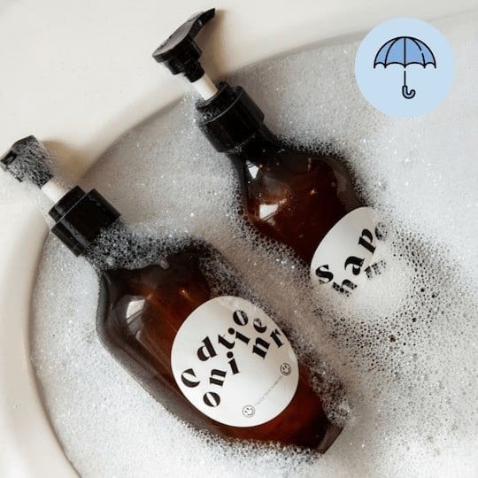 Bottiglie di sapone con etichette adesive immerse in acqua