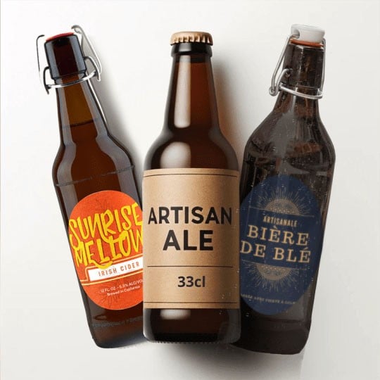 Tre bottiglie di birra con diverse etichette adesive personalizzate, una arancione, una marrone e una blu