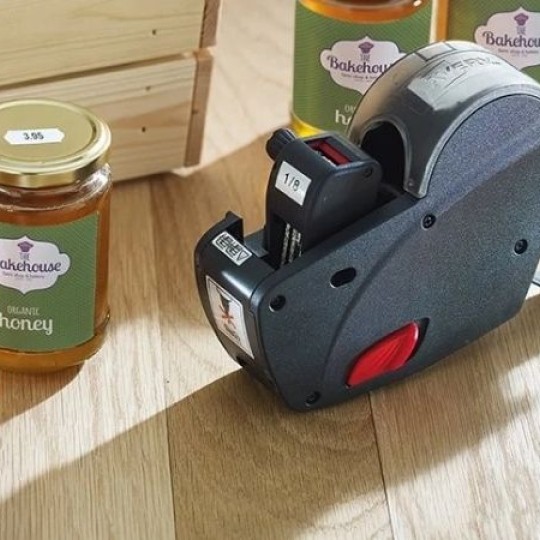 una prezzatrice accanto a dei barattoli etichettati