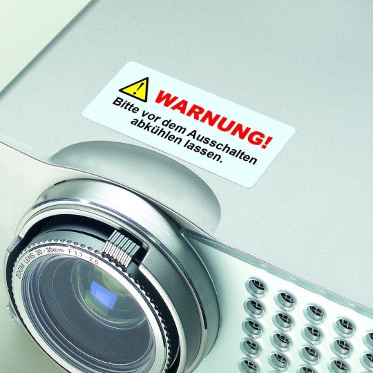 proiettore con applicata una etichetta rettangolare con scritta warning