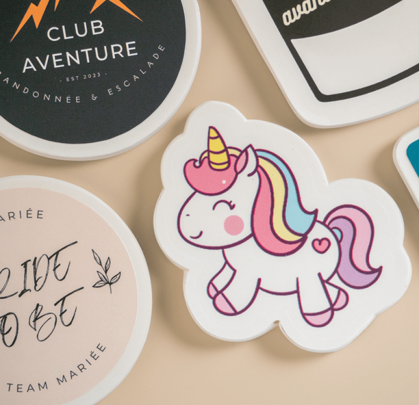 Adesivo di un unicorno sorridente con criniera arcobaleno e corno dorato, circondato da altri adesivi stampati
