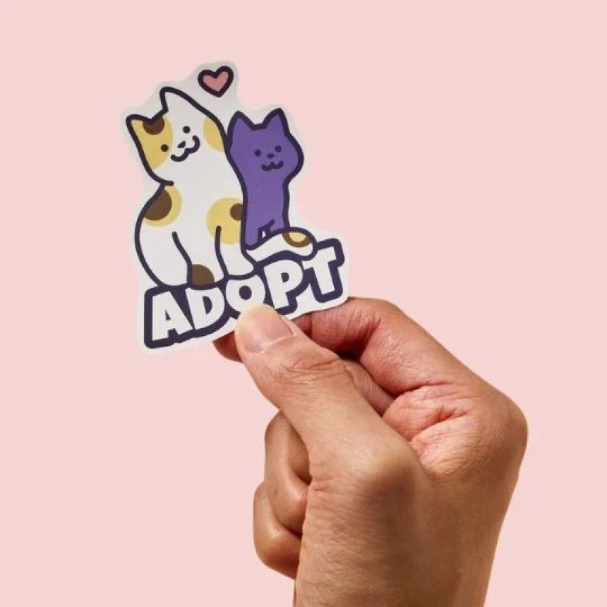 mano che tiene adesivo con stampati dei gatti