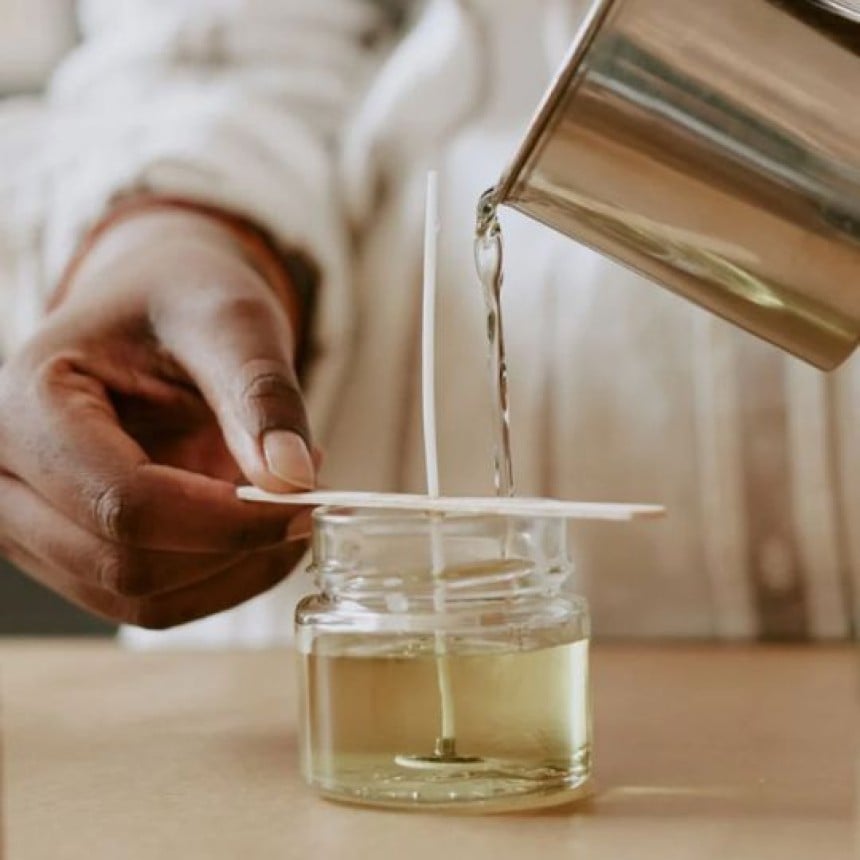 mani che mostrano come aggiungere l'olio essenziale nelle candele fatte in casa