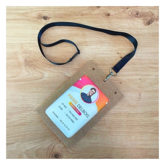 Lanyard with an ID card displayed on a wooden surface. The ID card includes a name, ID number, date of birth, and phone number, along with a photo.