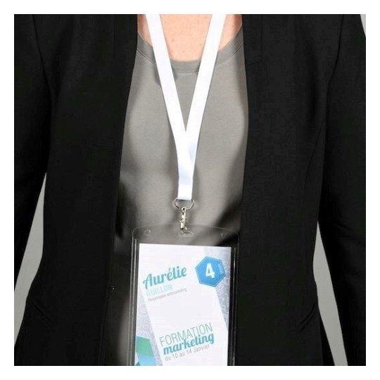 L'immagine mostra una persona che indossa un blazer nero con un badge appeso al collo. Il badge ha il nome 'Aurélie Guillon' e informazioni su una formazione di marketing.