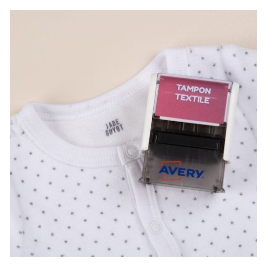 L' immagine mostra un body bianco con pois neri e un timbro Avery con la scritta 'TAMPON TEXTILE'.