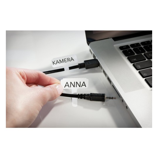 L'immagine mostra una mano che tiene un'etichetta con il nome 'ANNA', mentre un altro cavo etichettato 'KAMERA' è collegato a un laptop. I cavi sono neri e la superficie del laptop è argentata.