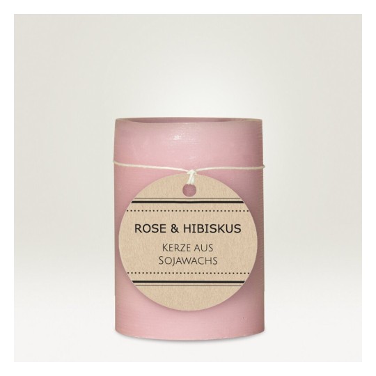 L'immagine mostra una candela rosa con un'etichetta che indica aromi di rosa e ibisco, realizzata in cera di soia.