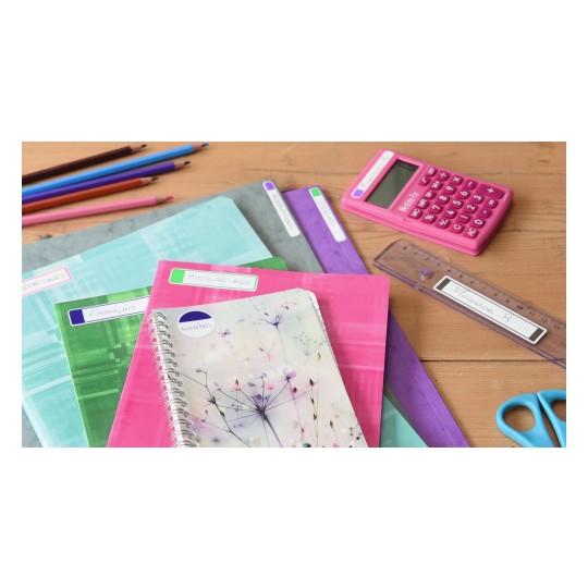 L'immagine mostra una serie di materiali scolastici tra cui quaderni colorati, un calcolatore rosa, un righello e forbici. I quaderni hanno etichette con nomi di materie scolastiche come 'Français' e 'Histoire-Géo'.
