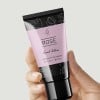 mano che tiene un tubetto di crema con applicata una etichetta rettangolare stampata
