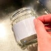 mano che mostra come rimuovere una etichetta con l'acqua