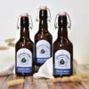 tre bottiglie di birra con applicate delle etichette a forma di arco stampate con il logo del birrificio
