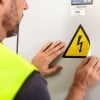 uomo che applicata un adesivo triangolare con stampato il simbolo del pericolo