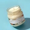 candela in vasetto di vetro con applicata una etichetta rettangolare stampata