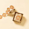 Rotolo di adesivi con la scritta 'Thanks for your love' e scatola di cartone con l'adesivo applicato