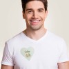 Uomo con maglietta bianca e cuore verde stampato su badge adesivo a forma di cuore sul petto