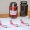 Due barattoli di marmellata con etichette sigillo stampate e foglio di etichette stampate sul tavolo