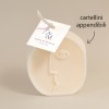 candela in cera con applicato un cartellino quadrato in carta con stampato il logo del marchio