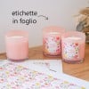 candele in vasetti rosa con applicate delle etichette quadrate stampate e fogli di etichette con la stessa stampa