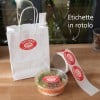 rotolo di etichette adesive ovali stampate accanto a busta bianca con lo stesso adesivo applicato