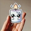 mano che mostra uno stickers stampato a forma di candela accesa