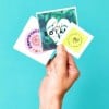 mano che tiene diversi stickers quadrati personalizzati con immagini e loghi