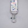 Lanyard with a floral design and a metal clip attachment.