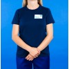 L'immagine rappresenta una persona in abbigliamento uniforme scuro, che sta in piedi con le mani incrociate, di fronte a uno sfondo blu.