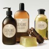 L'immagine mostra vari prodotti per la cura del corpo marchiati 'Lexure', tra cui uno shampoo, un gel doccia, una lozione per le mani e una saponetta verde, disposti su uno sfondo chiaro.