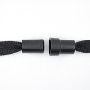 L'immagine mostra due estremità di una corda nera con coperture in plastica nera, collegate tra loro.