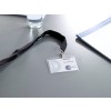 L'immagine mostra un badge identificativo con un laccio, sulla scrivania c'è un bicchiere d'acqua e un blocco note. Il badge riporta 'VISITEUR' e un nome.